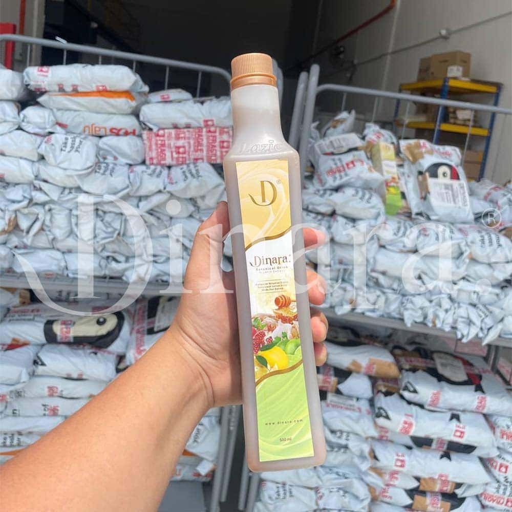 Dinarasli honey syrup bottle in hand with sugar bags in warehouse background.